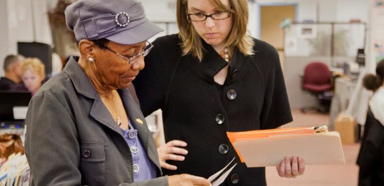 person helping older woman with paperwork